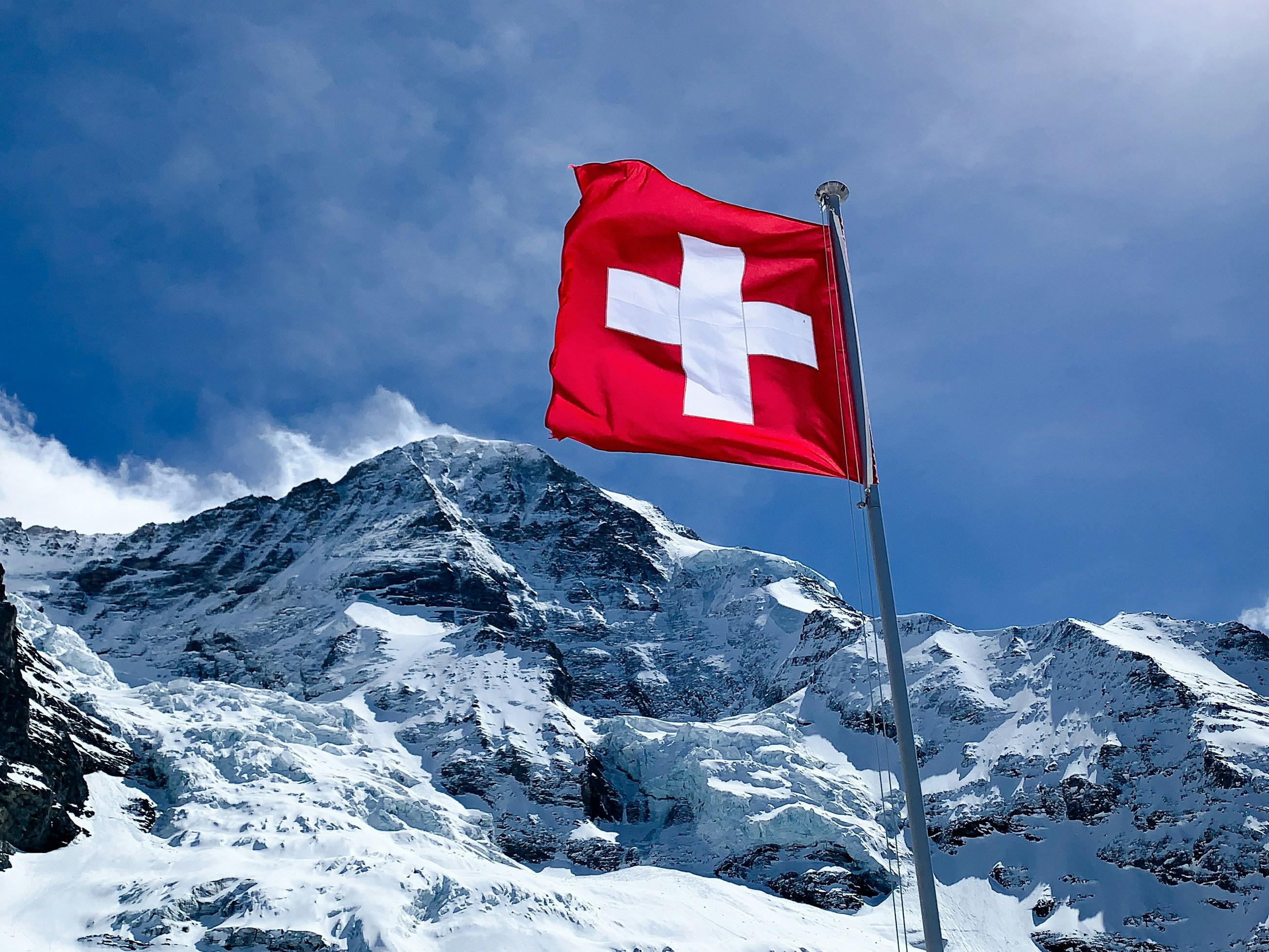 Drapeau suisse devant un paysage de montagne